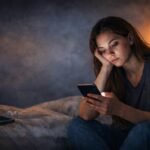 Young woman scrolling phone late at night feeling tired and disconnected